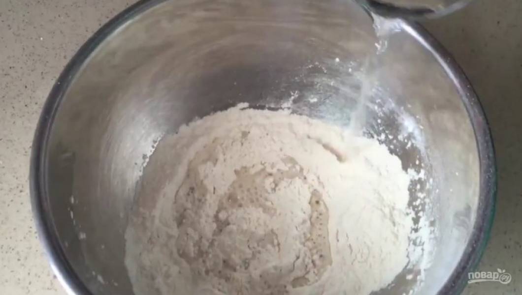 1. Муку, дрожжи и соль залейте теплой водой, перемешайте. Добавьте масло, замесите тесто. Накройте его полотенцем и оставьте подниматься на 30 минут.