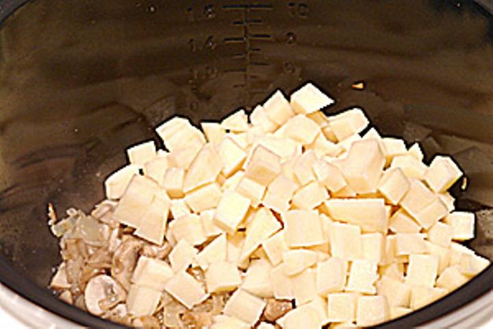 Картофель порежьте кубиками, отправьте в мультиварку к грибам. Немного пожарьте. Затем влейте бульон или обычную горячую воду. 