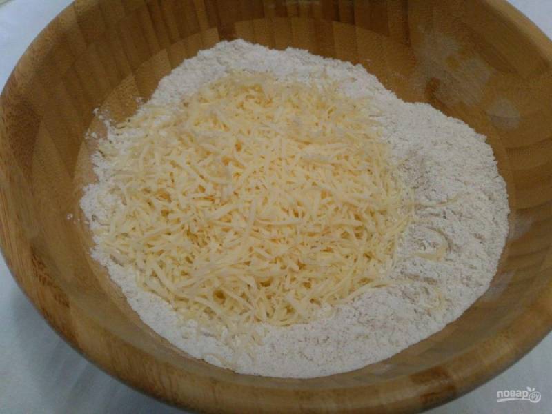 Добавьте к сухой смеси натёртый сыр, перемешайте ингредиенты с помощью ложки.
