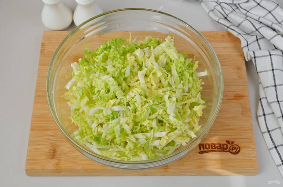 Нашинкуйте тонко пекинскую капусту, выложите в большой салатник.