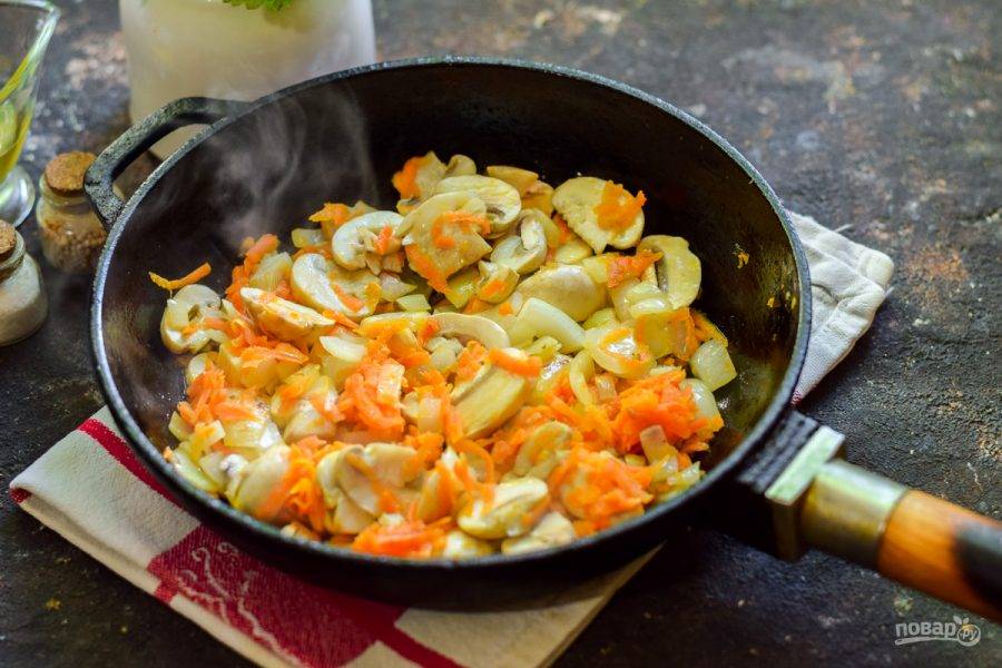 В сковороде разогрейте масло, выложите лук, морковь и грибы — жарьте 5 минут. Спустя время, когда картофель и гречка будут готовы, добавьте овощи. Варите суп еще 12 минут.