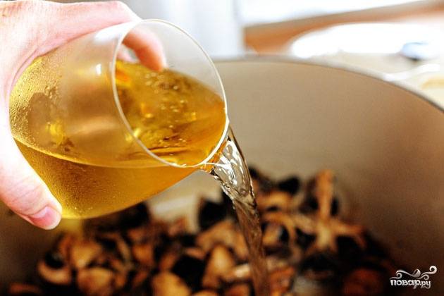 Когда грибы слегка размякнут и пустят сок, наливаем в кастрюлю вино. Выпариваем жидкость наполовину.