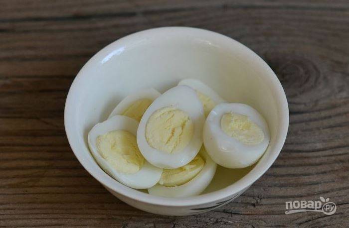 В сотейник или кастрюльку налейте воду и поставьте ее на плиту. Затем опустите в воду перепелиные яйца, доведите жидкость до кипения и варите их около пяти минут. Залейте яйца холодной водой, очистите от скорлупы и нарежьте кружочками. 