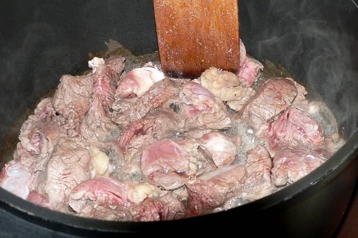 Итак, нарезаем мясо на небольшие кусочки и обжариваем его в казане или в высокой сковороде (со съемной ручкой) до легкого золотистого цвета. Затем наливаем в сковороду немного водички и отправляем мясо в разогретую до 180 градусов духовку, готовим его под крышкой в течение 1 часа.