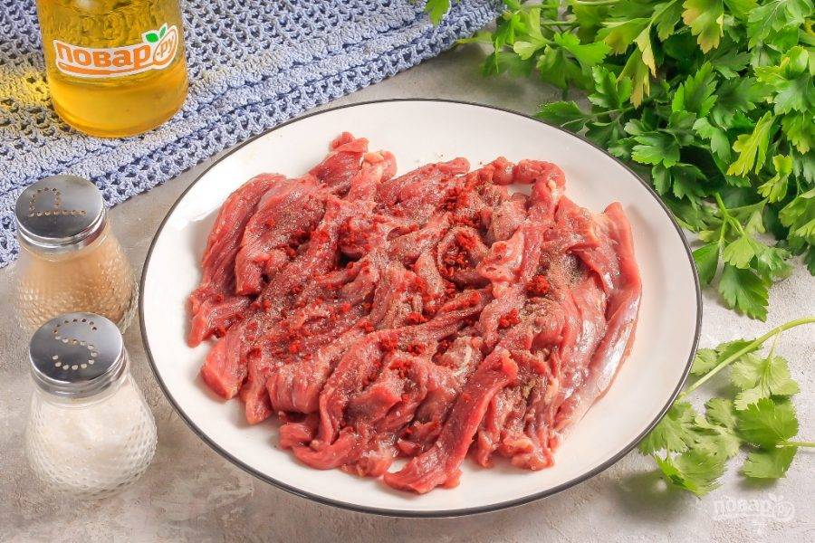 Мякоть говядины нарежьте на пластины, а их — соломкой, лентами. Посолите и поперчите мясо.