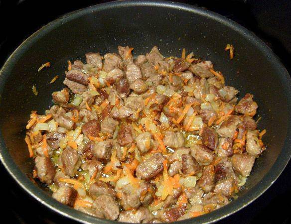 Морковь и лук измельчаем. В другой сковороде жарим тертую морковь с мелко нарезанным луком. Затем добавляем данную смесь в обжаренное мясо.