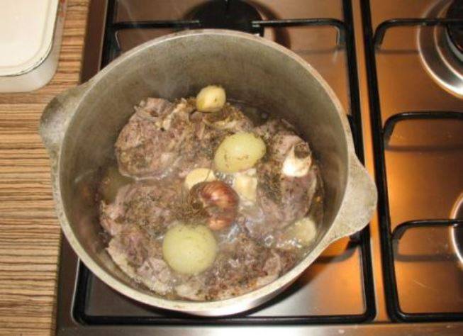 Затем удалите из мяса целые луковицы и чеснок. Положите в казан картофель, перемешайте, добавьте острую перчинку и варите до полуготовности картофеля.