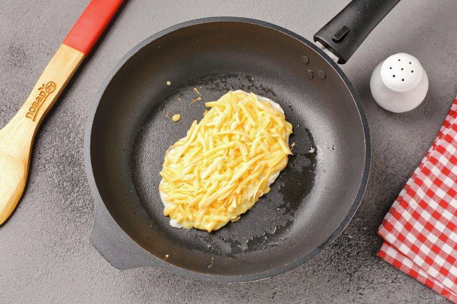Сверху посыпьте яйцо тёртым сыром.