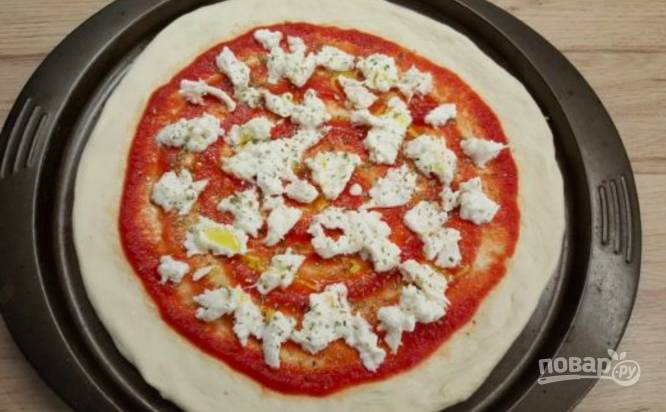 Покрошите моцареллу и разложите кусочки по всей поверхности пиццы. Присыпьте орегано, сбрызните маслом.