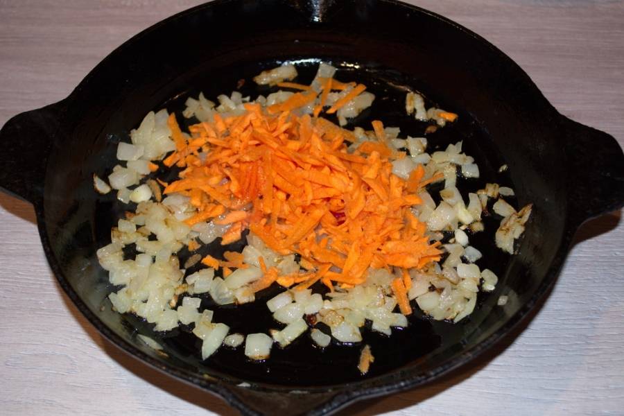 4. К обжаренному луку добавьте натертую морковь. Тушите, периодически помешивая, до мягкости.