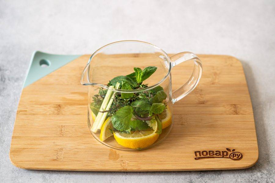 В заварочный чайник уложите мяту, чабрец, лимон, лемонграсс, разрезанный вдоль и лайм.