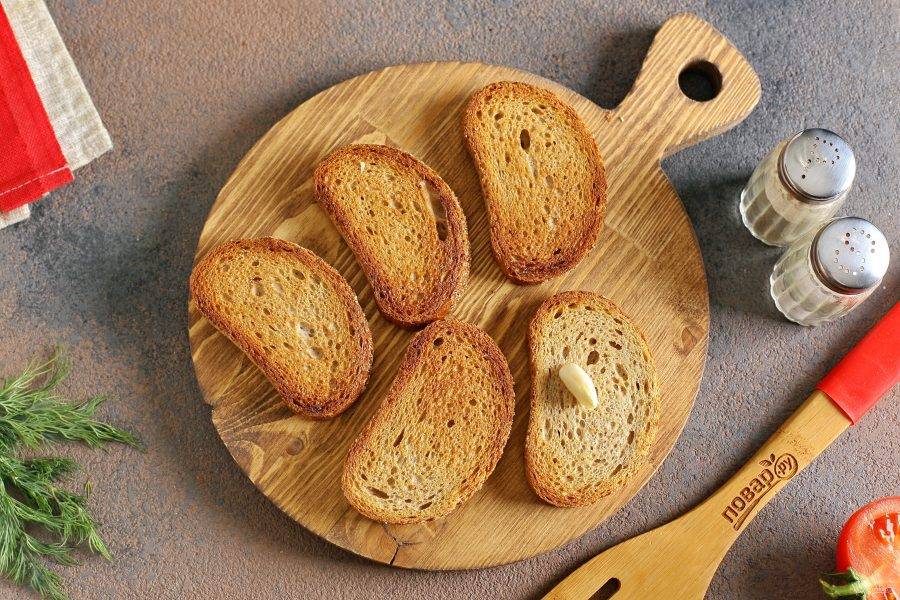 Хлеб подсушите на сковороде с одной стороны. Натрите подсушенную сторону зубчиком чеснока.