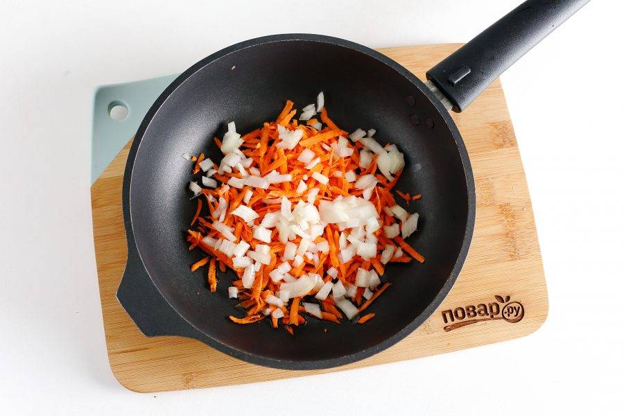Разогрейте сковороду с маслом. Выложите нарезанный кубиками лук и тертую морковь.