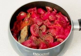 Добавьте помидоры к баклажанам, присыпьте специями и солью. Тушите под крышкой 15 минут.