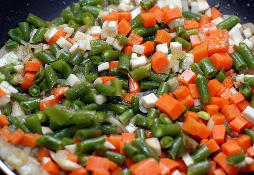 Добавляем морковь, фасоль и сельдерей. Перемешиваем и тушим под крышкой 15 минут.