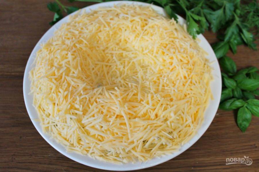 Твердый сыр трем на терке. Выкладываем сыр на салат, формируя "гнездо".