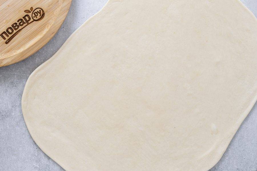 Раскатайте тесто в тонкий прямоугольный пласт. Смажьте растительным маслом.