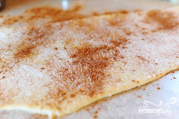 3. Раскатать тесто в прямоугольник 20Х75 см. Залить сливочным маслом, затем равномерно посыпать сахаром и корицей равномерно по поверхности. 
