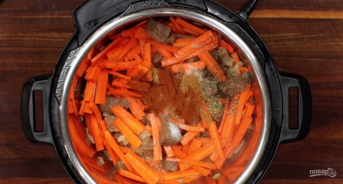 3. Нарежьте морковь и лук, измельчите чеснок. Добавьте овощи к мясу. Посыпьте кориандром, паприкой, тмином и черным перцем. Продолжайте готовить мясо с овощами в скороварке.