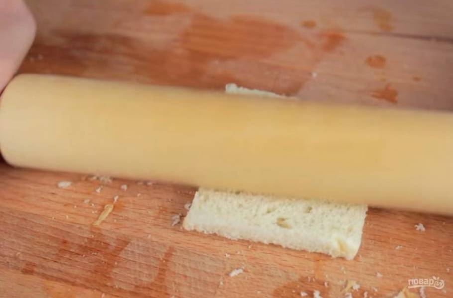 1. Для начала возьмите ломтики хлеба и отрежьте твердую корочку. Затем с помощью скалки раскатайте хлеб в тоненькую пластинку. 