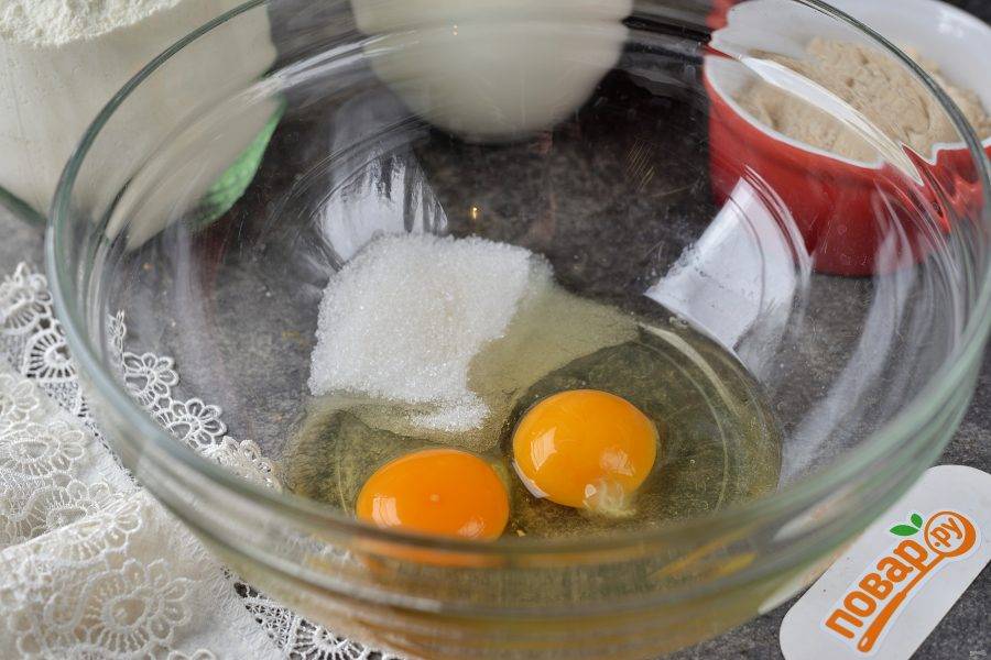 Вбейте в глубокую миску два небольших яйца, всыпьте сахар и взбейте в однородную пену. 