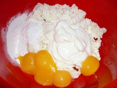1. В глубокую мисочку выложить творог и сметану. Разбить яйца, добавив сюда желтки (а белки в отдельную мисочку). Всыпать крахмал и начать взбивать массу. 