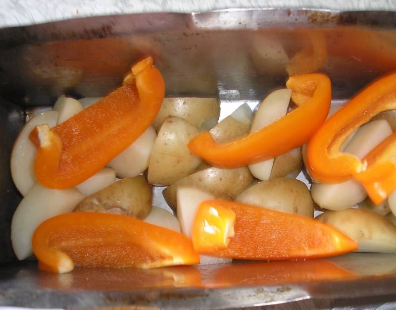 Перец порежьте крупными дольками и вместе с картофелем сложите в форму для запекания. 