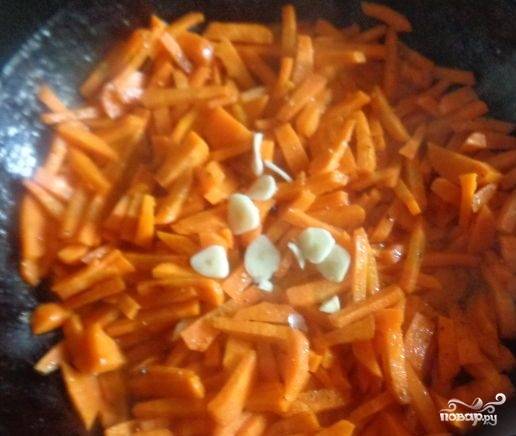 4. В сковороду кладем морковь, в середине жарки добавляем нашинкованный мелко чеснок и продолжаем обжаривать.