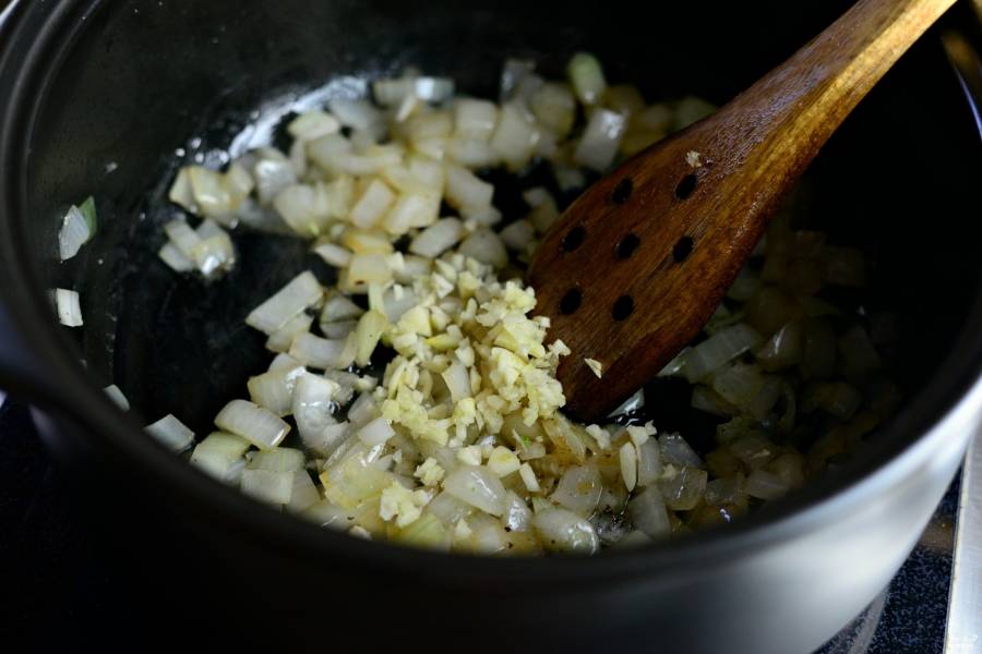 Шаг 5. Нарежьте мелко лук и чеснок. Поджарьте их на среднем огне до мягкости и золотистости лука.