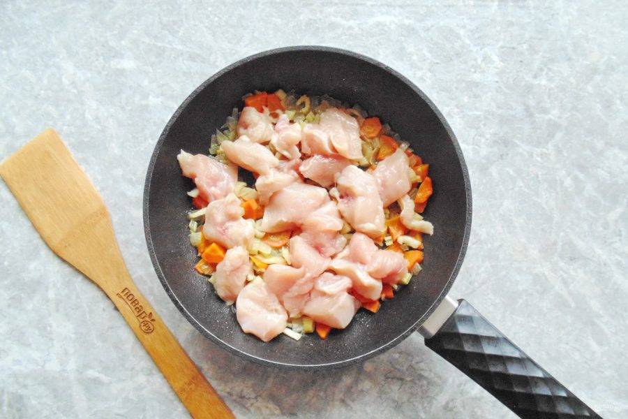 Куриное филе нарежьте небольшими кусочками и переложите в сковороду к овощам. Продолжайте тушить помешивая ещё 7-8 минут.