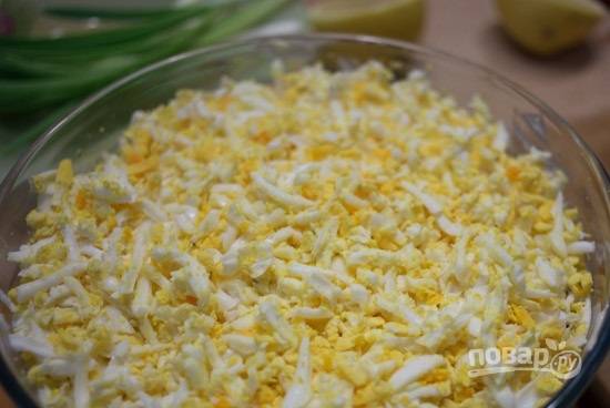 Теперь выложим половину натертого на мелкой терке сыра и натертые на крупной терке яйца. Смазываем майонезом.