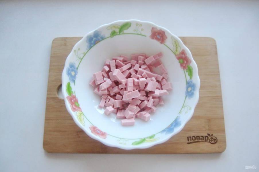 Вареную колбасу нарежьте мелкими кубиками.