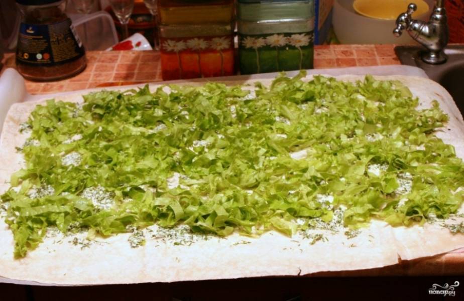 Затем равномерно разложите по поверхности лаваша нарезанные ранее салатные листья. 