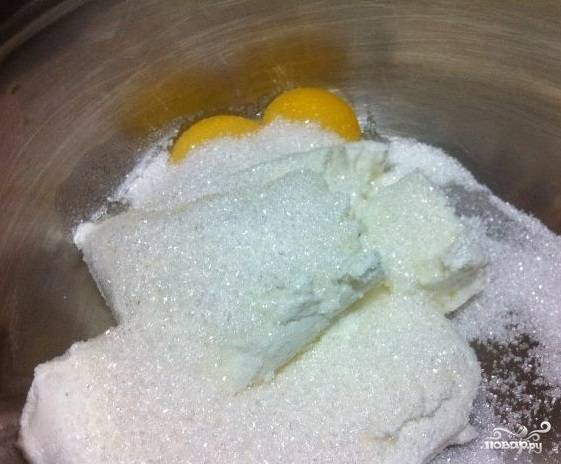 1. Перед тем, как приготовить творожник классический, отделите желтки от 2 яиц. Далее добавьте творог и 3 ст. ложки сахара. Все перемешайте до однородной консистенции.