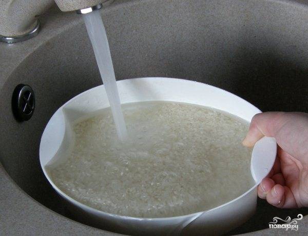 Рис тщательно промыть большим количеством воды, перетирая его в ладонях, чтобы избавиться от верхней оболочки зерна. 