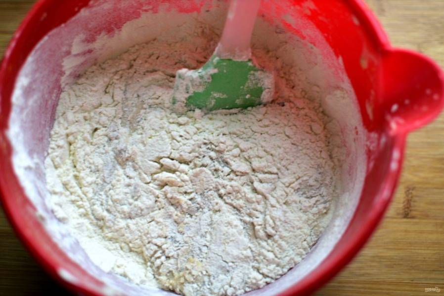 Всыпьте просеянную с содой и разрыхлителем муку, добавьте щепотку соли. Лопаткой перемешайте тесто, не добиваясь особой однородности.