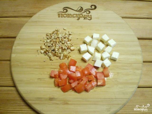 Порежьте кубиками сыр и помидор. Очищенные орехи порубите ножом мелко.