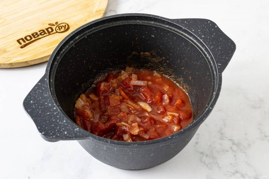 Добавьте к луку томаты в собственном соку. Потушите на медленном огне 5 минут, периодически помешивая.