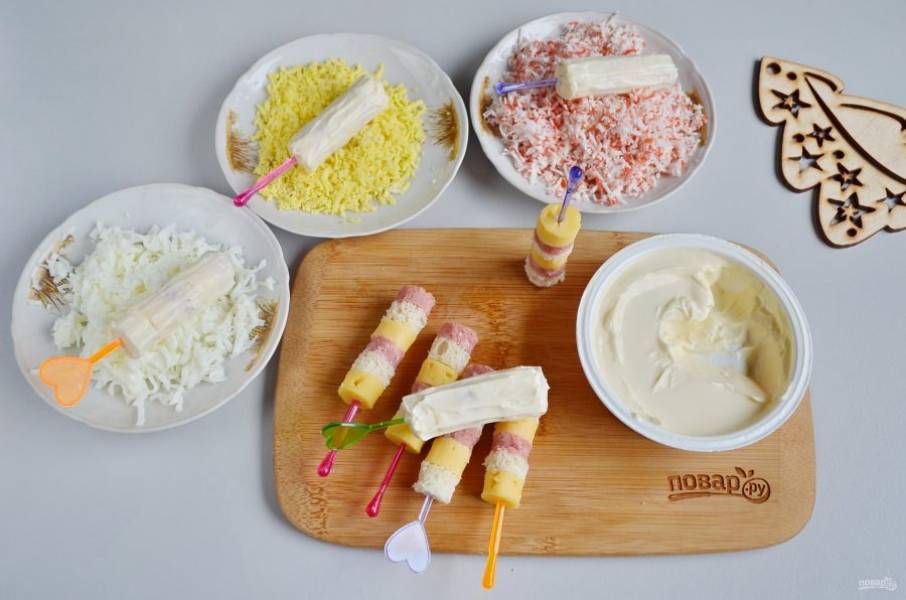Каждый бутербродик тщательно смажьте сыром со всех сторон. Обваляйте канапе в разных посыпках: в желтке, белке или крабовых палочках.