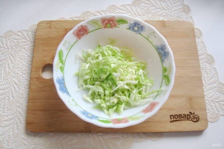 Молодую белокочанную капусту нарежьте тонкой соломкой и немного помните руками. Выложите в салатник.
