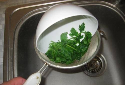 Закидываем зелень в миску и заливаем ее крутым кипятком из чайника, даем постоять зелени в кипятке минуту, после чего откидываем петрушку на дуршлаг и даем стечь воде.