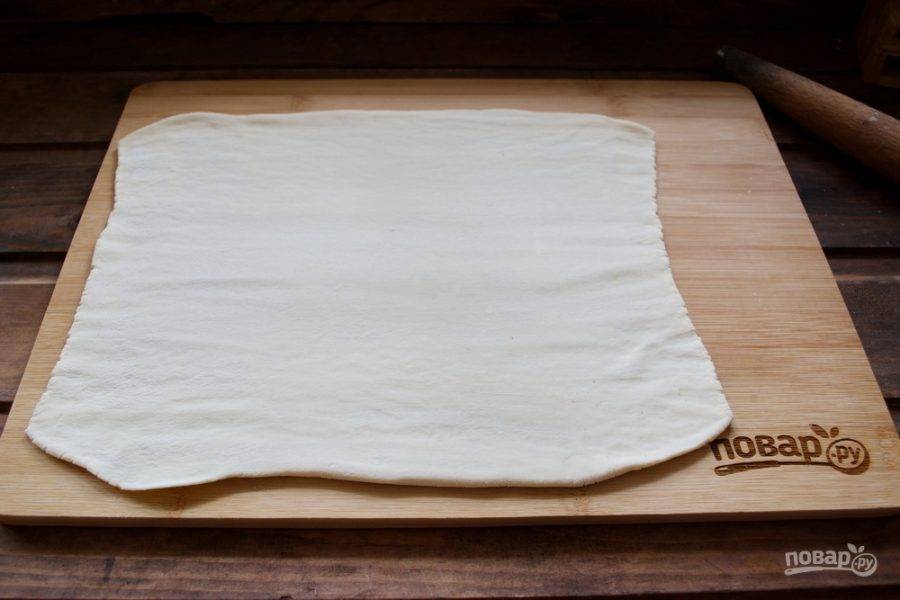 Доску присыпьте мукой. Выложите на нее тесто и раскатайте его в тонкий пласт толщиной 1-1,5 см.