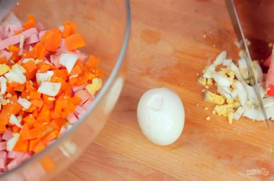1. Сначала приготовьте сам салат. Для этого нарежьте небольшими кубиками отваренный картофель, колбасу, отваренную морковь, яйца и все огурцы. Затем измельчите зелень и добавьте в салат. 