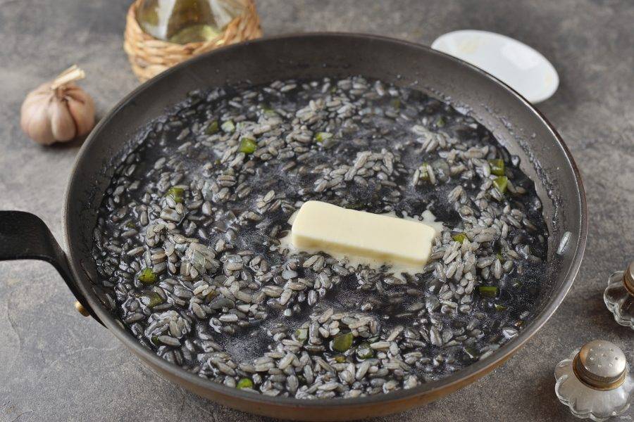 На этом этапе рис уже будет альденте, добавьте кусочек сливочного масла. Если хотите хорошо проваренный рис, тогда подливайте бульон и держите до полной готовности.