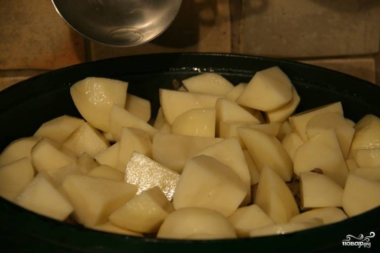Пока мясо с овощами тушится, порежьте картошку и чеснок. Выложите их поверх мяса в чугунок. И отправьте все под закрытой крышкой в духовку часа на полтора при 160 С. 