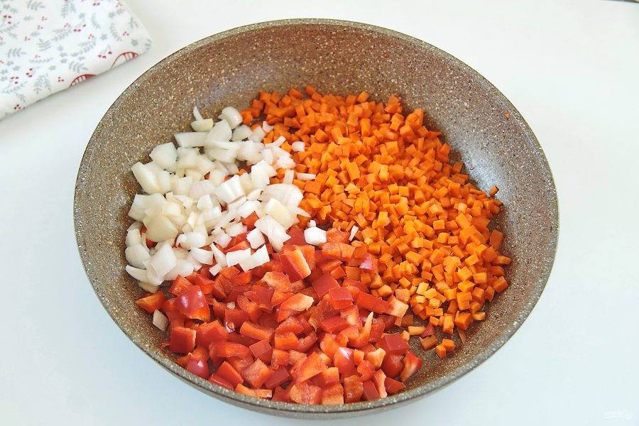Нарежьте кубиками морковь, перец и лук. Сложите в сковороду и налейте масло.