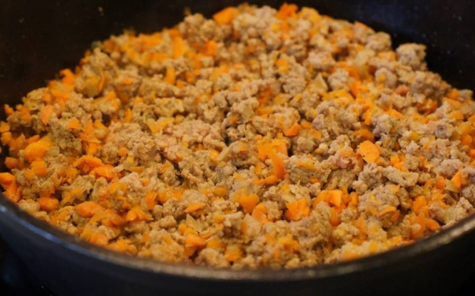 Измельчите лук и морковь и обжарьте их в глубокой сковороде. Затем добавьте фарш, специи, перемешайте и жарьте вместе еще минут 15. 