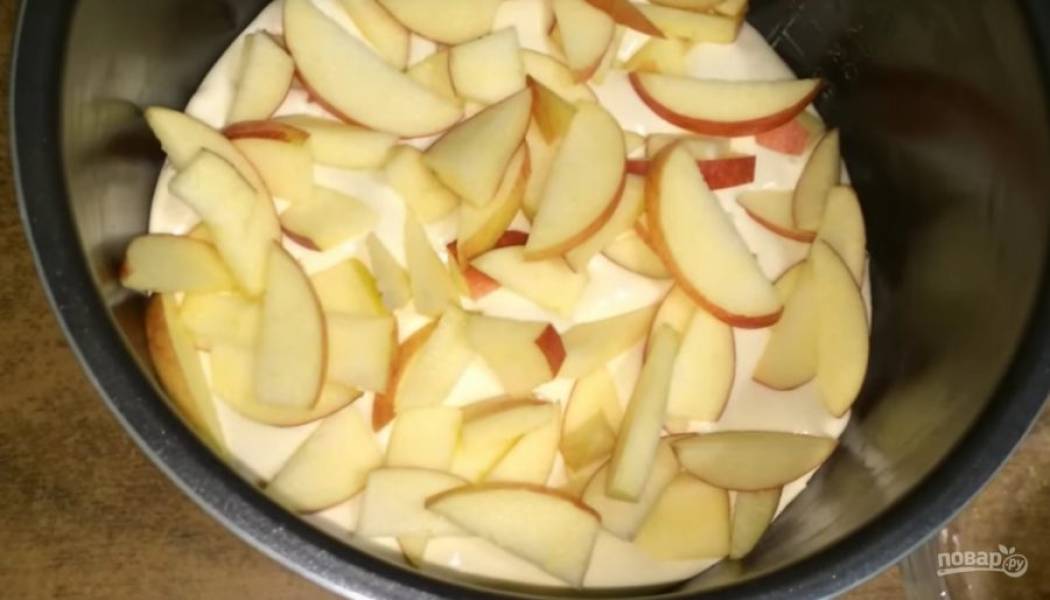 Форму для запекания смажьте сливочным маслом (я пеку пирог в мультиварке). Выложите в форму тесто. А сверху — яблоки. Яблоки можно выкладывать вниз, можно "в середину" теста. 