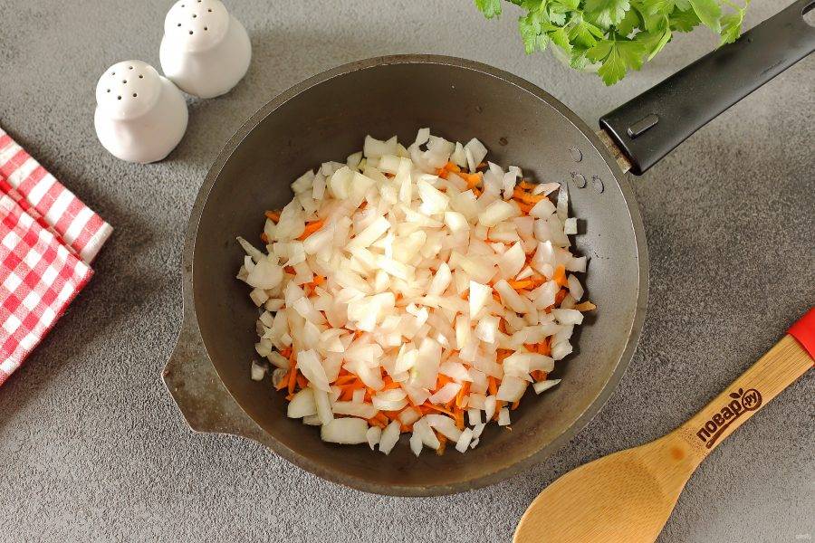 В сковороде разогрейте масло, выложите нарезанный кубиками лук и тертую морковь. Готовьте овощи до мягкости.