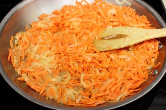 Добавьте морковь и жарьте ее 5 минут под крышкой. 